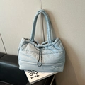 Light blue quilted puffer tote bag with drawstring closure on a leather sofa - Haze Blue Without Charm