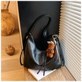 Dettaglio della borsa hobo in ecopelle nera con ciondolo a orsetto e nappa intrecciata - Nero con ciondolo