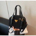 Detailed view of the black nylon handbag featuring gold triangular logo and leather handles - Black