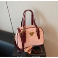 Detail of pink suede handbag featuring burgundy leather handles and vintage metal logo - Pink