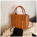 Detail der braunen Plissee-Beuteltasche mit weicher Textur und Knotengriff-Design - Braun