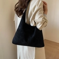 Minimalist black matte faux suede tote bag shown on model with hobo style design - Black