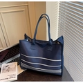 Detalle del bolso tote de lona a rayas azul oscuro en un ambiente minimalista - Azul