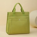 Dettaglio di borsa tote in tela verde con tasca frontale e bottone automatico in argento - Verde