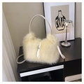 Detalle de un bolso de felpa suave con correa de cuero sobre un mueble negro minimalista - Amarillo
