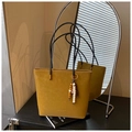 Detalle de bolso tote de cuero mate jengibre con colgante de madera y correas negras finas - Marrón
