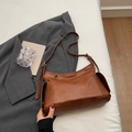 Minimalist caramel brown leather hobo bag with adjustable strap in a lifestyle setting - Brown (No Pendant)