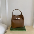 Brown lychee leather bucket handbag with gold buckle and top handle in a cozy setting - Brown No Pendant