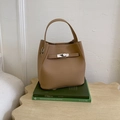 Camel leather bucket bag with top handle and metal lock clasp displayed on vintage books - Khaki No Pendant