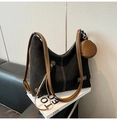 Détail du grand sac cabas noir mat avec bandoulières marron et pendentif sur canapé - Noir