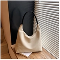 Détail du sac hobo en toile crème minimaliste avec poignées en cuir noir sur bois - Blanc Cassé
