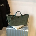 Borsa tote in pelle scamosciata verde scuro capiente mostrata in una scena di viaggio - Verde
