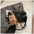 Detail der schwarzen PU-Lederhandtasche mit Plüschhund-Anhänger und gewebten Akzenten - Schwarz mit Anhänger