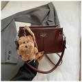 Nahaufnahme einer dunkelroten Vintage-Umhängetasche mit Logo und Plüschhund-Anhänger - Rot mit Anhänger