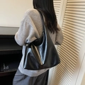 Minimalistische zwarte lederen hobo-tas met gouden logo gedragen over de schouder - Zwart