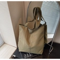 Primer plano de un bolso tote de lona verde oliva con costuras verticales y etiqueta - Verde