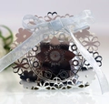 Close-up of laser-cut silver wedding favor box with floral patterns and a blue ribbon - Reflective Silver