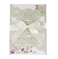 Macro detail of laser-cut snowflake wedding invitation with glitter and satin bow - Light Gold Glitter