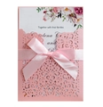 Detail of pink laser cut wedding invitation with floral pattern and satin ribbon bow - Pink