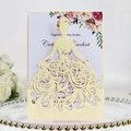 Detailed laser-cut ivory dress-shaped wedding invitation on a golden bead glass tray - Beige Jewelry Star