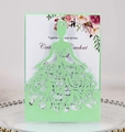 Detail of laser-cut dress-shaped wedding invitation with floral printed inner card on a tray - Fruit Green