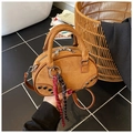 Close-up of brown suede handbag with woven rope charm and metal rivets on marble background - Brown with Pendant