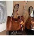 Detalle del bolso tote de ante marrón oscuro con asa de cuero y colgante de osito suave - Marrón con colgante