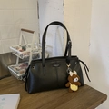 Detail of black tote bag with dual straps, metal buckle and brown plush bear charm accessory - Black with Pendant