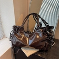 Dark brown glossy crossbody bag with drawstring pleated details in a lifestyle setting - Coffee