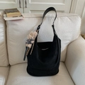 Borsa hobo scamosciata nera con ciondolo a forma di orsetto marrone su divano beige - Nero con ciondolo
