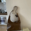 Detailed view of brown leather tote bag with heart charm and woven tassel detail - Brown (With Pendant)