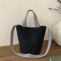 Detailed view of black suede bucket bag with chevron patterned strap on rustic wood - Black