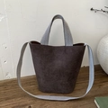 Detail der dunklen Wildleder-Eimertasche mit schwarz-weißem Chevron-Muster-Gurt - Braun
