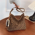 Leopard print shoulder bag with beaded charm and adjustable leather strap on table - Leopard Print With Charm
