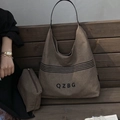 Borsa tote in tela marrone e astuccio coordinato con logo QZBG su una panca in legno - Marrone