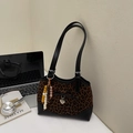 Leopard print tote bag with black leather trim, bow detail and heart charm on desk - Black And Coffee With Pendant