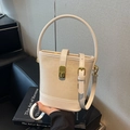 Elegant creamy white bucket bag featuring a gold lock and circular handle in a lifestyle setting - Off White