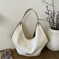 Chic beige hobo tote bag with brown trim and pleated texture on dark wood surface - White