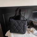 Black quilted tote bag with wide shoulder strap for women in a modern office setup - Black