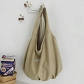 Detail der khakifarbenen Nylon-Tragetasche mit weißem Logo-Etikett an einem Metallhaken - Khaki