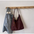 Detail der burgunderroten Hobo-Tasche mit dekorativen Holzperlen und Lederquasten am Haken - Rot mit Anhänger