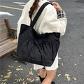 Bolso tote negro de lona con lazos ajustables y bolsillos laterales, vista de estilo urbano - Negro
