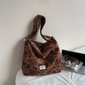 Brown canvas tote bag with paisley pattern and wide strap for women shown on a bed - No Pendant / Brown