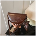 Detail of dark brown saddle bag with glossy oil-wax finish and heart silk scarf - Brown