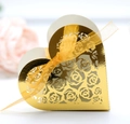 Goldene herzförmige Geschenkbox mit hohlem Rosenmuster und orangefarbenem Band für Hochzeiten - Reflektierendes Gold