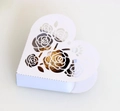 Detail der weißen herzförmigen Geschenkbox mit lasergeschnittenem Rosenmuster und Praline - Weiß