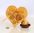 Detail der goldenen herzförmigen Geschenkbox mit Rosenmuster und gelber Schleife - Gold