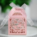 Close-up of laser-cut pink birdcage candy box with intricate floral patterns and white ribbon - Pink