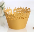 Macro detail of gold laser-cut lace cupcake wrappers with crown and cake patterns - Gold