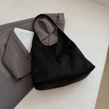 Suede black large tote bag shown on grey suit blazer for a modern minimalist fashion look - Black